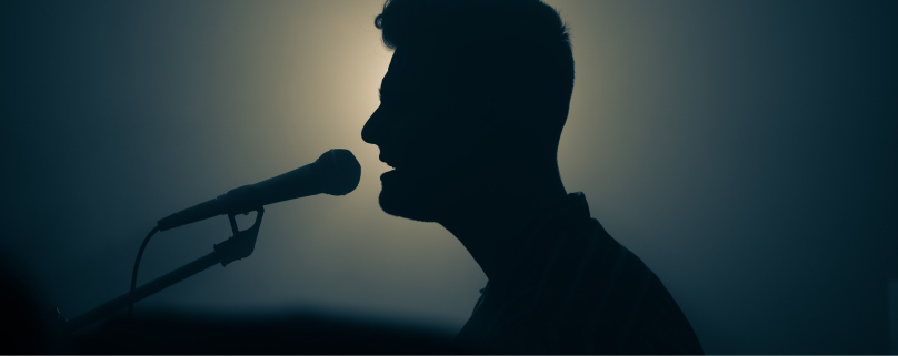 Silhouette of a male singer performing with a microphone.