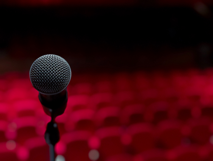 Close-up of a microphone with blurred-out seating in the background.